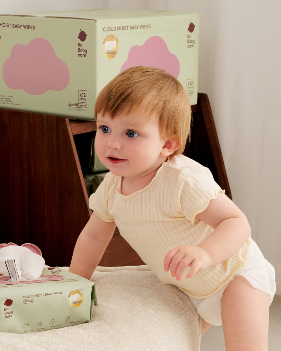 Baby leaning on a sofa beside Cloud Moist baby wipes